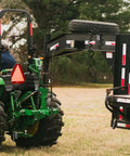 Dual Design Gooseneck Tractor Trailer Hitch With Hay Bale Spear Charcoal Frame Two Inch Receiver Mount And Two Five Sixteenth Inch Gooseneck Ball attached to tractor in field