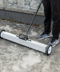 Heavy Duty 24 Inch Rolling Magnetic Pickup Sweeper With Adjustable Handle collecting nails and screws on concrete surface.
