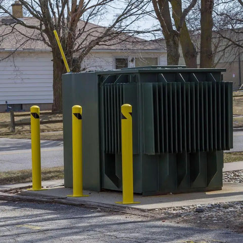 Heavy Duty Beefy Steel Safety Barrier Bollard And Industrial Traffic Control Post With Rock Solid Bright Yellow Finish And Concrete Fillable Base Plate For Warehouse Machine Guard At 42 Inches in urban setting next to electrical transformer.