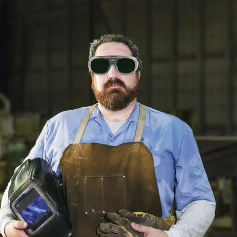 Heavy Duty Pair Of Welding Goggles With Double Layer Plastic Lens on a worker in a shop, wearing safety gear and gloves.