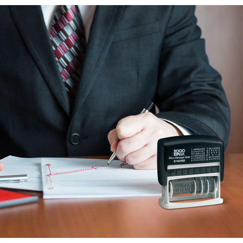 Slick Self Inking Micro Message Dater Stamp with Quick Flip Phrases for Office Organization on a desk with a suited professional.