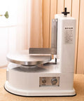 Smooth Operator Automatic Cake Cream Smoothing Machine With Button Press Controls And Custom Thickness Adjustments For Show Stopping Frosting Finishes Lightweight Pink Tool on a table with a metal frosting plate.