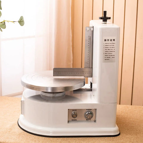 Smooth Operator Automatic Cake Cream Smoothing Machine With Button Press Controls And Custom Thickness Adjustments For Show Stopping Frosting Finishes Lightweight Pink Tool on a table with a metal frosting plate.