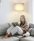 Slick Adjustable Plug In Pendant Light With Authentic Beige Linen Shade illuminates cozy reading nook with woman and dog on sofa.