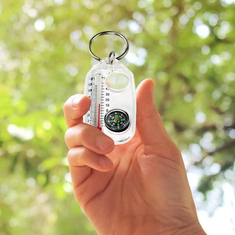 Hand holding Sturdy Outdoor Compass Keychain For Backpacking And Travel, Pocket Size Navigation Gadget with ABS build and thermometer.