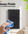 Person cleaning a Slick Glossy Black Decorator Wall Outlet with a cloth in a bright living space.