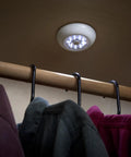 9-LED Anywhere Light XB Black 3 Pack With Ultra Bright Floodlight illuminating a clothing closet, easy install on ceiling with adhesive