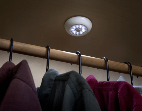 9-LED Anywhere Light XB Black 3 Pack With Ultra Bright Floodlight illuminating a clothing closet, easy install on ceiling with adhesive