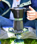 Bold Black Nine Cup Stovetop Espresso Maker Moka Pot on portable stove for outdoor coffee brewing.