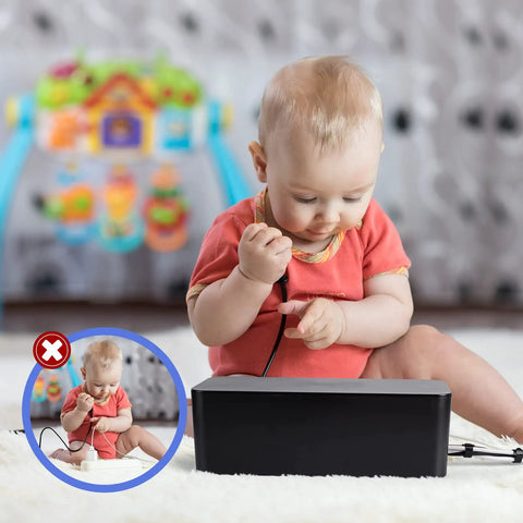 Baby sitting near a closed black cable organizer box with cords, showcasing the Triple Cable Organizer Box Set for Desk Tidy Up Wires Like a Pro With Large, Medium, and Small Cord Management Boxes, Power Cover Cord Holder and Surge Protector Black.