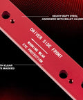 Red anodized steel manifold drill template for GM LS engines (1999–2007) to remove broken exhaust bolts; driver side front.