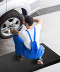 Mechanic working on car using Industrial Grade Anti Fatigue Mat For Standing Comfort All Day 3x5 Ft Thick 15/16 Inch Ergonomic Floor Mat