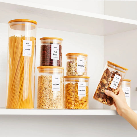 Airtight Glass Storage Jars Set Of 7 With Bamboo Lids For Pasta Cookies Nuts Coffee Beans Cereal Flour Pantry Organization BPA Free Clear Glass Canisters, neatly filled with pasta, beans, oats, and cereal on a shelf.