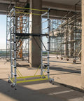 Heavy Duty Aluminum Scaffold Tower Ready To Roll Work Platform Adjustable Utility Scaffolding With Hatch Deck And Guard Rail 500 Pounds Capacity in a construction site.