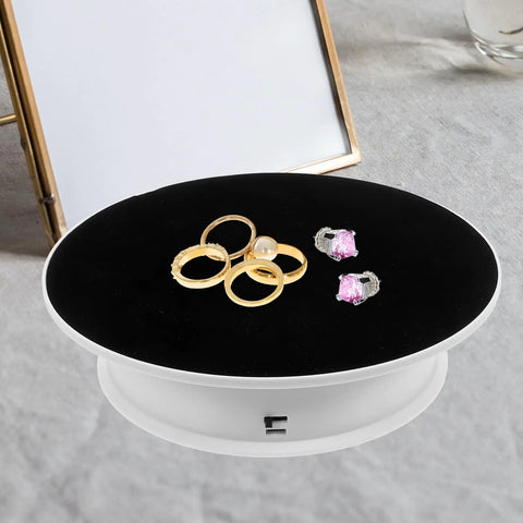 Ultimate 360 Degree Electric Turntable Rotating Display Stand With Two-Speed Adjustment For Jewelry Watches Photoshoot And Commercial Showcase Using White Base And Black Velvet Surface showcasing gold rings and pink earrings.