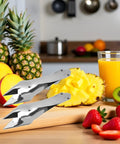 Stainless Steel Pineapple Eye Remover And Core Cutter With V Shaped Tip, alongside fruits and juice on kitchen counter.