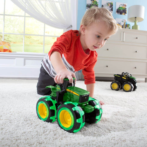 Child playing with John Deere Monster Treads Lightning Wheels Monster Truck Toy With Motion Activated Lights on carpet
