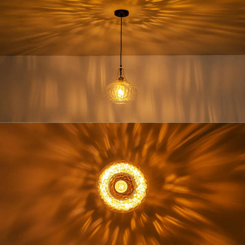 WILON 11" Hammered Glass Pendant Lights Kitchen Island Black hanging above, casting warm light with intricate shadow patterns.
