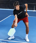 Person playing pickleball with CP7 8 Oz Pickleball Paddle Lightweight Carbon Fiber With Textured Surface For Ultra Spin, Power And Control