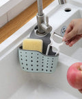 Double Deck Faucet Mount Kitchen Sink Organizer With Adjustable TPR Rubber Sponge Soap And Scrubber Storage Basket over sink, holding sponge and peeler.