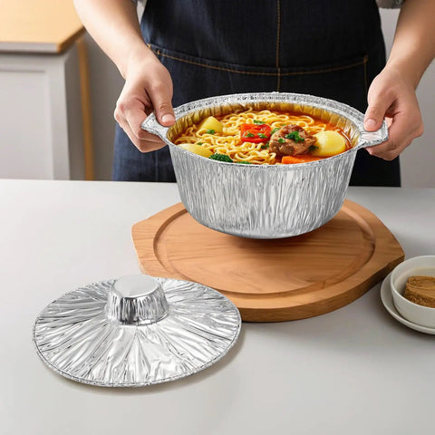 Person holding Disposable Aluminum Pots With Lids 10 Pack 2 Liter Round Foil Pan Food Containers For Camping Picnics Travel Heating And Cooking Easy Cleanup Great For On The Go Meals filled with soup