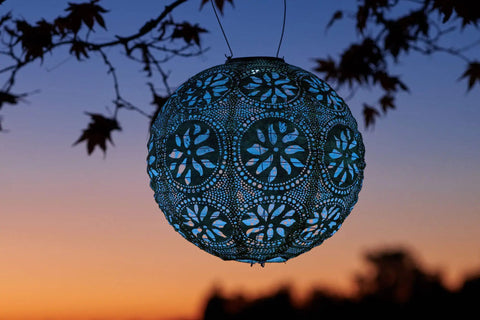 Boho Outdoor Solar Lantern With Weatherproof Tyvek Fabric, dual white LEDs illuminating in a garden setting at sunset.