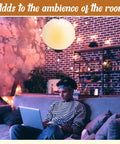 Jumbo 30 Inch White Paper Lanterns Hanging Luminaries For Weddings And Events in a cozy living room setting with a person on a laptop