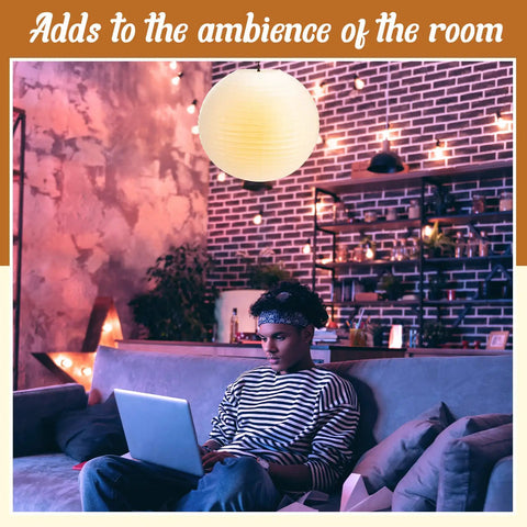 Jumbo 30 Inch White Paper Lanterns Hanging Luminaries For Weddings And Events in a cozy living room setting with a person on a laptop