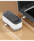 Portable Ultrasonic Cleaner With Rechargeable Battery For Jewelry And Watches on a desk, charging via USB next to a laptop.