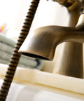 Close-up of the spout and hose of an Antique Vintage Brass 6 Inch Centers Two Handle Clawfoot Bathtub Faucet Set With Deck Mounted Shower Combo.