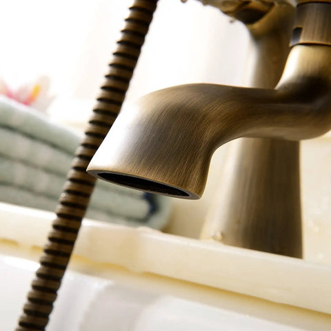 Close-up of the spout and hose of an Antique Vintage Brass 6 Inch Centers Two Handle Clawfoot Bathtub Faucet Set With Deck Mounted Shower Combo.