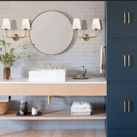 Two Light Wall Sconce With White Fabric Tapered Shades In Dope Antique Brass Finish for a bathroom vanity setting, dimmable LED.