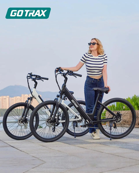 Woman standing with 26 Inch Electric Bike With 350W Brushless Motor Up To 20 MPH, 30 Mile Pedal Assist Range, Front Shock, 7-Speed, Adjustable Seat, Commuter Cruiser For City Rides, Black.