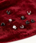 Metal slider retainers on red fabric for Zipper Repair Kit With Metal Insertion Pins, Slider Retainers, And Top And Bottom Stops, 80 Piece Set