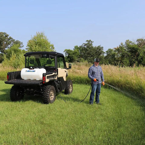 A person using a 40 Gallon Deluxe UTV Spot Sprayer With 2.2 GPM 70 PSI Max, mounted on a utility vehicle in a grassy field.