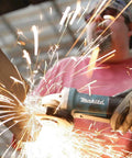Worker using Paddle Switch 4-1/2 Inch Angle Grinder With 7.5 Amp Power on metal, sparks flying