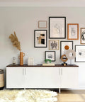Modern living room with white cabinet, framed art, plants, and decor pieces on a shelf