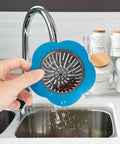 Holding a blue Colorful Silicone Kitchen Sink Strainers Set Of 4 With Large 4.5 Inch Wide Rim above the sink