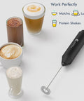 Mini Handheld Milk Frother Wand With Stainless Steel Whisk Battery Powered Drink Mixer For Coffee Lattes Cappuccinos And Matcha No Stand Needed Portable Barista Style Foam On The Go Gift For Coffee Lovers Black shown next to frothed coffee drinks.