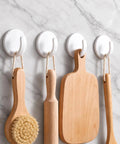 Eight Piece White Peel And Stick Wall Hooks Offer A Super Strong Hold that organizes wooden kitchen utensils on a marble wall.