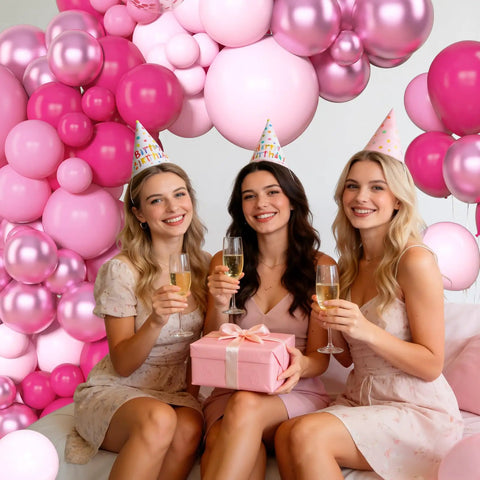 Three women celebrating with an All In One Hot Pink Balloon Arch Garland Kit With 153 Latex Balloons behind them.