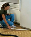 Person using Long Reach Vacuum Extension Attachment with 36 inch reach and flat hose design for deep cleaning under fridge, gray finish.