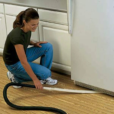 Person using Long Reach Vacuum Extension Attachment with 36 inch reach and flat hose design for deep cleaning under fridge, gray finish.