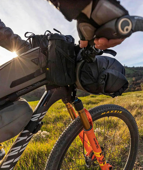 Cyclist with FrontLoader Bike Front Bag 8L for light camping gear, green durable water-resistant build on front frame, weekend ride