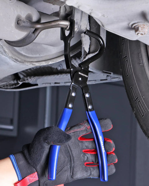 WORKPRO exhaust hanger removal tool with blue-handled pliers used under a car to detach a rubber exhaust hanger.