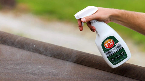 Hand spraying Outdoor Fabric Guard Restores Water Repellency To Factory New Levels onto brown fabric surface