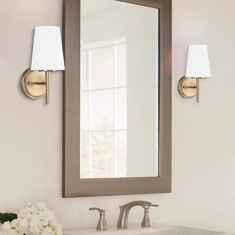 Driscoll One Satin Brass 1 Light Wall Sconce Vanity Fixture For Wet Locations beside a bathroom mirror over a sink