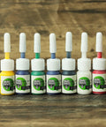 Color pack bottles for Four Coil Tattoo Machine Kit Set For Lining Shading And Coloring, assorted colors on wooden surface.
