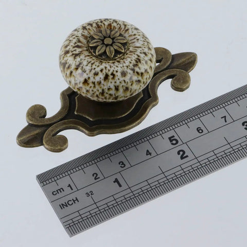 10 Pack White Ceramic Dresser Knobs With Bronze Backplates Retro Furniture Hardware Handles next to a ruler for size reference