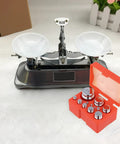 12 Piece Calibration Weights Set With Tweezers And Storage Box Pro Grade High Precision Steel Weights For Digital Scales Including 1g 2g 5g 10g 20g 50g 100g 200g 500g M1 Chrome Plated next to a mechanical balance scale.